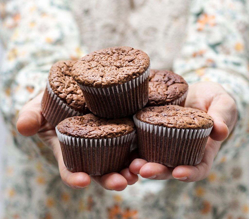 a woman holds five cupcakes in her hands. low-carb diets cause us to crave sugary foods